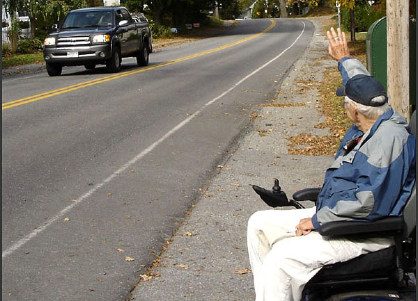 Kermit "Kert" Ingraham waves at an oncoming vehicle from the end of his driveway on Washington Street in Camden Tuesday. (Photo by Chris Wolf)
