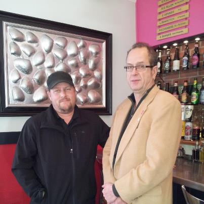 Artist Eric Leppanen and Cafe Miranda chef/owner Kerry Alterio stand in front of Leppanen's artwork featured in the restaurant. (Photo courtesy Cafe Miranda)