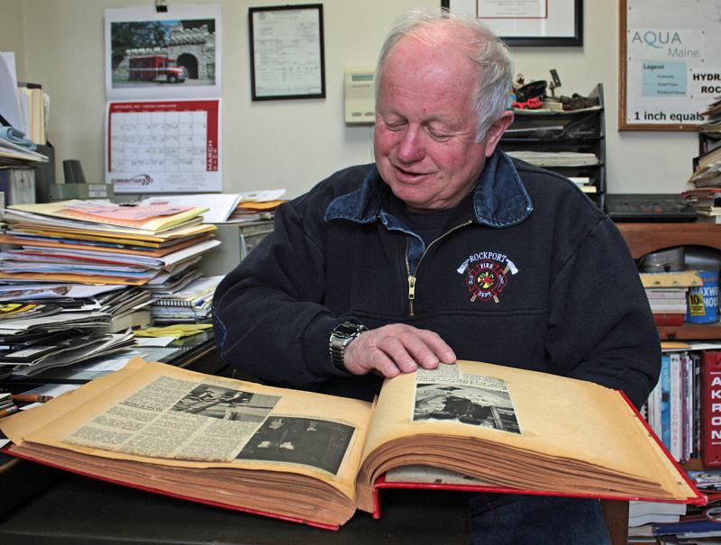 Bruce Woodward takes a look at a scrapbook his mother had been keeping, with news clippings going back his being named Rockport Fire Chief in 1971. (Photo by Holly S. Edwards)