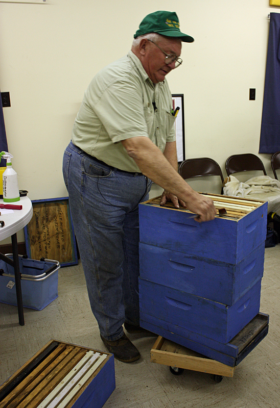 Peter Lammert stacks three medium hive boxes and shows how a tool can be used to pry apart frames stuck together by the bees with propolis. (Photo by Holly S. Edwards)