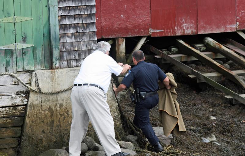 Chief Randy Gagne and ACO Jeff Sukeforth follow the fawn on the slippery rocks at low tide. (Photo by Holly S. Edwards)