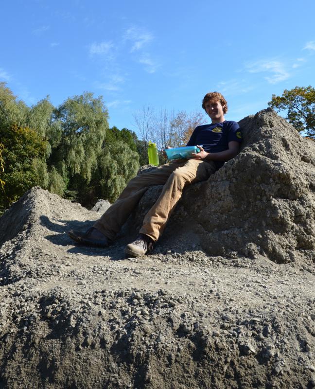Ethan Harding, from Waldo County and with the Maine Conservation Corps, takes lunch on a throne of path construction material. (Photo by Lynda Clancy)