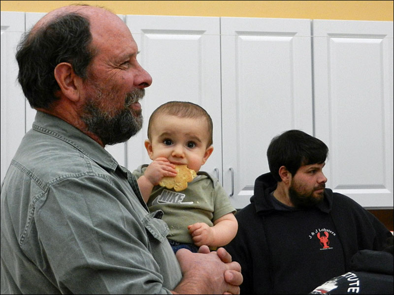 Little Eli in the arms of his grandfather, Clayton Philbrook, with Eli’s dad, Nick, in the background. (Photo by Eva Murray)