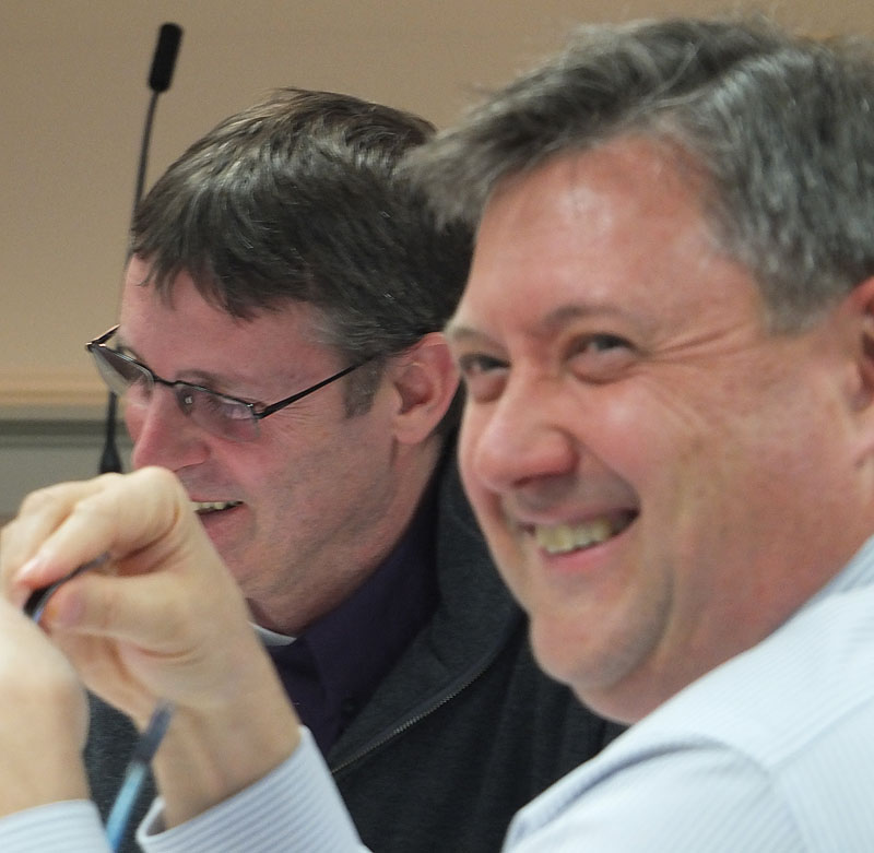 Councilor Eric Hebert (foreground) and Tom Luttrell share a laugh during Monday's meeting.