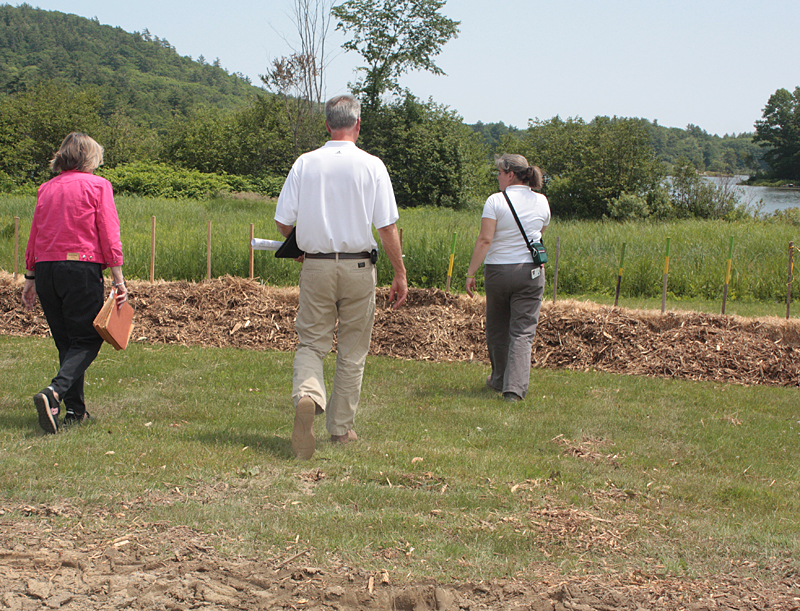 Pat Finnigan, Will Gartley and Dawn Hallowell walk toward the erosion berms above the shoreline of Hosmer Pond. (Photo by Holly S. Edwards)