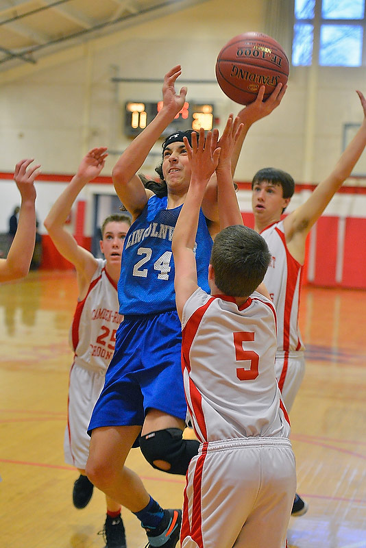 Lincolnville’s Ionut Lodge, center, drives hard to the basket in a sea of Camden players drawing the foul in the process. (Photo by Ron Hawkes)