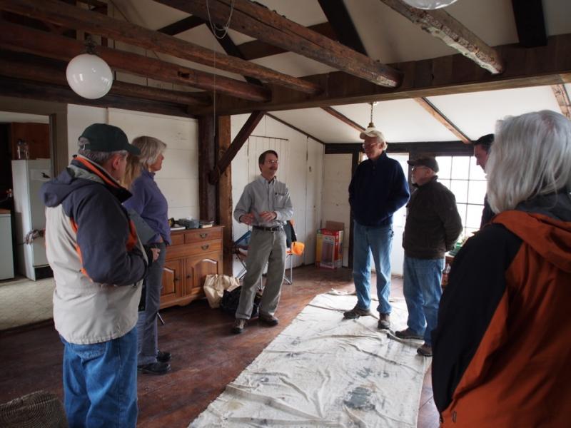 Evergreen Home Performance Energy Advisor Brian Robinson (center) explains the air sealing and insulation upgrades made at the Langalis homestead to Land Trust Board Members, staff, and volunteers