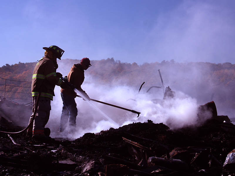 Warren fighters late Monday morning put water to some hotspots where the Martin farm’s barn once stood. (Photo by Holly S. Edwards)