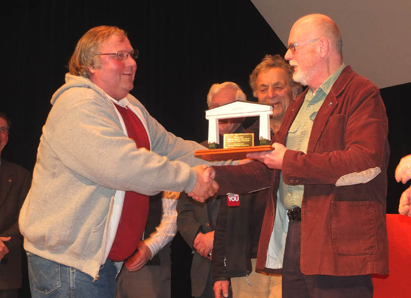 Camden Select Board Chairman John French gives Rockport Select Board Chair Bill Chapman the award for winning the first-ever toboggan competition between the two towns.