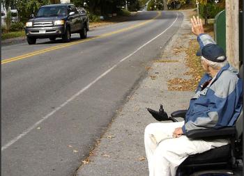 Kermit "Kert" Ingraham waves at an oncoming vehicle from the end of his driveway on Washington Street in Camden Tuesday. (Photo by Chris Wolf)