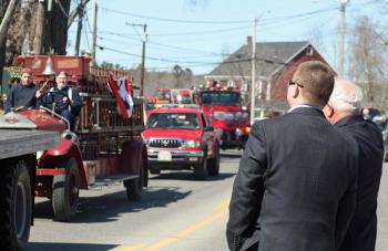 Andy Woodward stands on Route 1 with his dad, retiring Rockport Fire Chief Bruce Woodward, as Bruce greets dozens of fire trucks parading in his honor. (Photo by Holly S. Edwards)