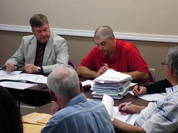 Regional School Unit 20 Board Chairman Anthony Bagley, right, tabulates weighted votes in a close decision on a change to the draft 2013-14 budget. At left, Superintendent Brian Carpenter. (Photo by Ethan Andrews)