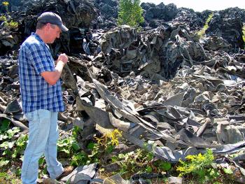 Michael Parker of the Maine Department of Environmental Protection lifts some of the synthetic upholstery stockpiled on the property of a defunct shooting range in Warren. DEP is seeking proposals for reusing the material, which currently poses a fire hazard. (Photo by Ethan Andrews)