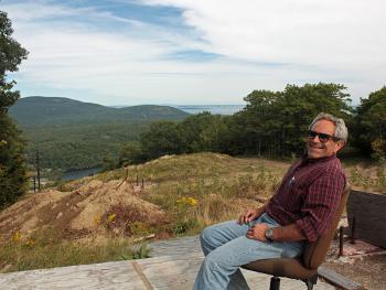 Camden Snow Bowl Facilities Manager Bill ‘Fitzy’ Fitzcharles sits on the platform footing that was the end of the ride on the old double chairlift. (Photo by Holly S. Edwards)