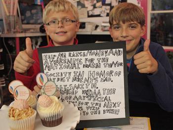 From left, Jacob Murray and his ‘best friend’ Will Smith pose with the sign Jacob wrote to announce the fundraiser he created to help raise money for the National Brain Tumor Society. Smith’s father, Billy Smith, was diagnosed with a brain tumor two years ago, which today shows no sign of growth but causes minor health issues for the Rockland Police officer and firefighter. (Photo by Holly S. Edwards)