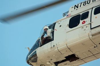 One of the helicopter’s two pilots watches out the window as he works to lower the cable hook to the crew below, so they can grab it and attach it to cable hook attached to the chairlift towers. (Photo by Holly S. Edwards)