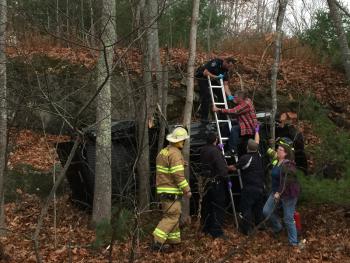 Guyer ‘Gordon’ Guist is assisted down off his overturned truck to be evaluated by North East Mobile Health emergency medical technicians, who later transported him, seemingly uninjured, to Pen Bay Medical Center. (Photo by Holly S. Edwards)