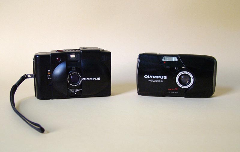 A pair of compact 35mm cameras, one of which the author tries to keep in a front pocket or otherwise nearby.