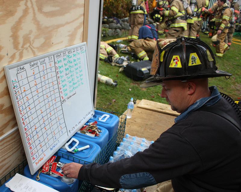 South Thomaston Fire Chief Bryan Calderwood checks the board, radios assignments and resets the safety tags to account for everybody on the fire scene. (Photo by Holly S. Edwards)