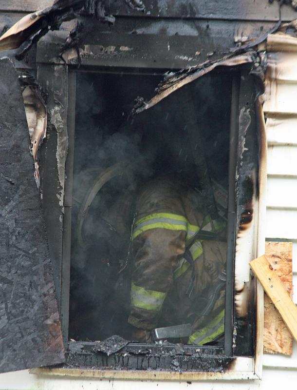 A firefighter works inside on the second floor of the house. (Photo by Holly S. Edwards)