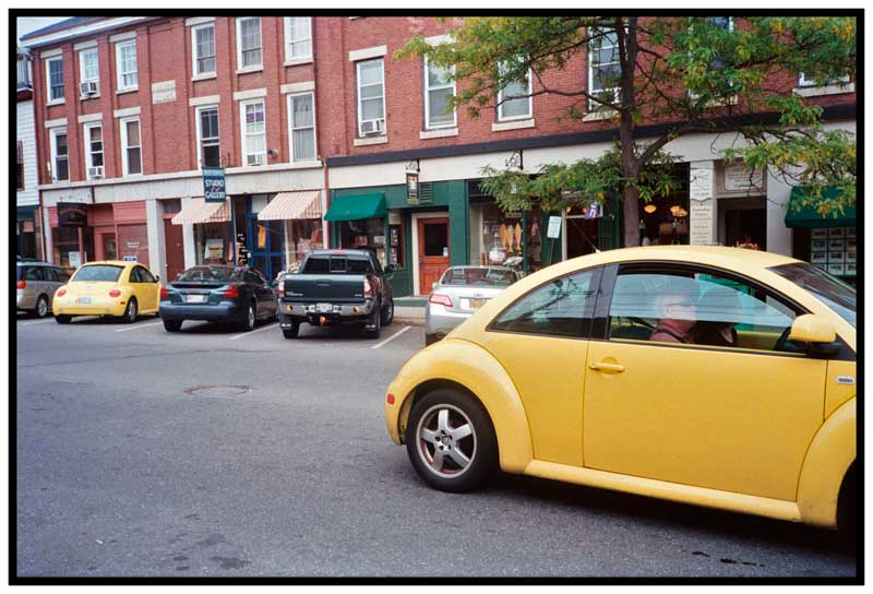 BELFAST – A pair of yellow Volkswagen Beetles flank a truck with a pair of yellow and black yin yang bumper stickers