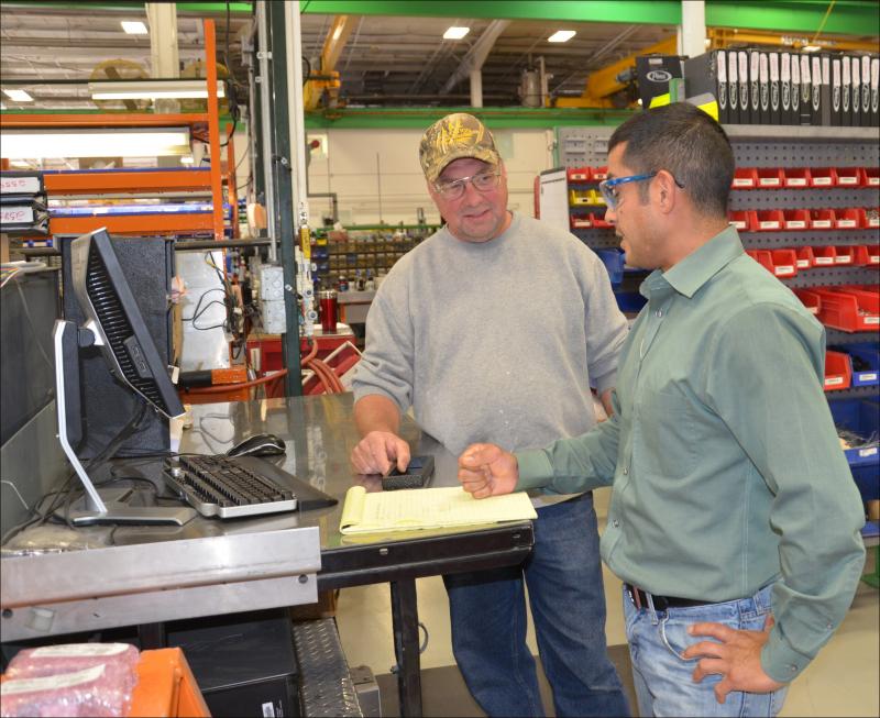 Steve Koehnke and Ike Beltrand review electrical systems at Pierce. Ike, an electrical mechanical designer who grew up in Los Angeles, has been at Pierce seven years. Steve has been there for 27 years, and now oversees 15 electrical engineers, who concentrate just on the trucks' command center electronics: "That's not the cab, not the chassis, not the pump, not the body nor the aerial device," said Ike. (Photo by Lynda Clancy)