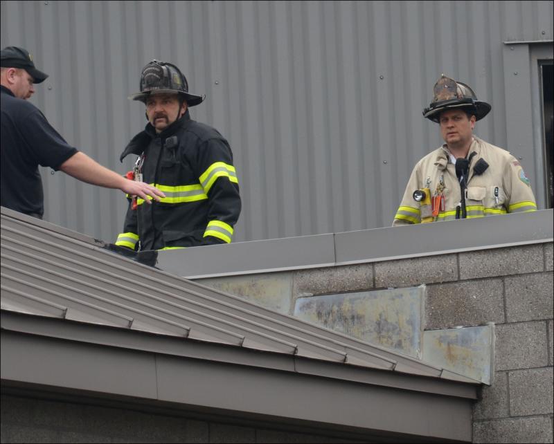 Rockland firefighter Francis Johnson and Asst. Chief Adam Miceli assess the roof of Knox County Jail for the source of smoke in the building. (Photo by Lynda Clancy)