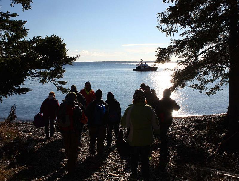 The volunteers playing plane crash victims in the Oct. 13 mass casualty drill arrive on the beach with a Coast Guard Auxiliary vessel in the background. (Photo by Holly S. Edwards)