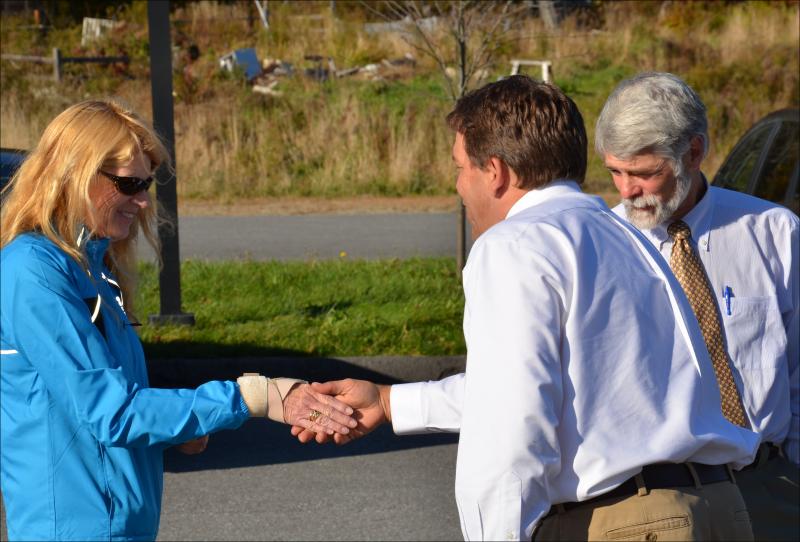 Marianne Smith shakes hands with Stephan Keenan, of Keenan Auction Company, just before going to cast the winning bid at the foreclosure auction of Farmers Fare, on the corner of Cross Street and Route 90 in Rockport on Oct. 18. Her husband, Stuart, is to her left. (Photo by Lynda Clancy)