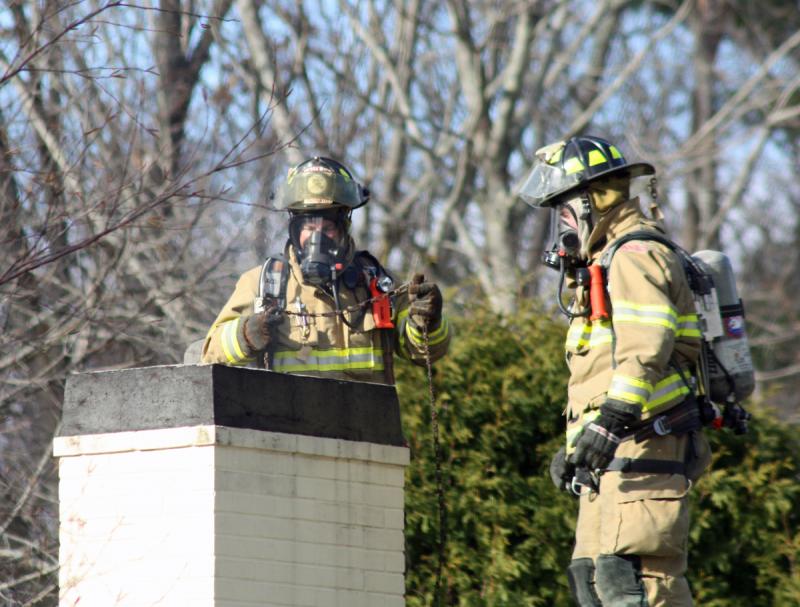Camden firefighters Bob French Jr. and Ryan Fisher on the roof clearing a chimney fire at 26 High St. Thursday morning. (Photo by Holly S. Edwards)