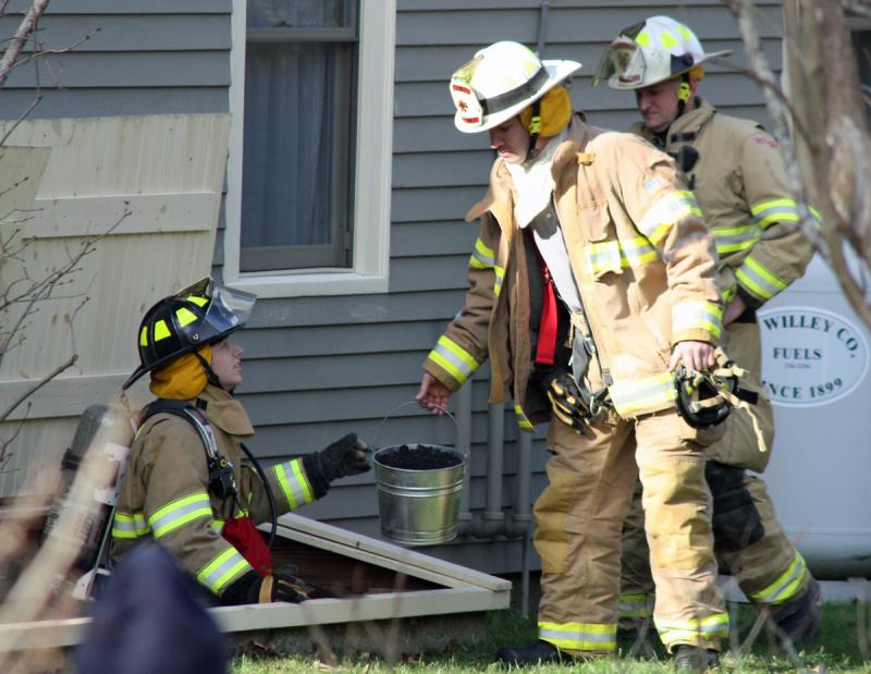 From left, Camden firefighter Scott Entwistle passes a bucket of debris cleared from inside the chimney to Asst. Chief Andrew Lowe, with Chief Chris Farley in the back. (Photo by Holly S. Edwards)