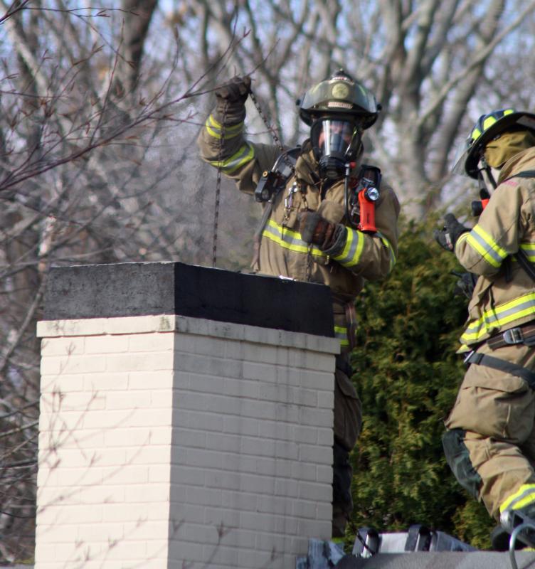 Camden firefighter Bob French Jr. uses a balled-up bunch of chain to clear a smoldering fire and debris from inside a chimney at 26 High St. Thursday morning. (Photo by Holly S. Edwards)