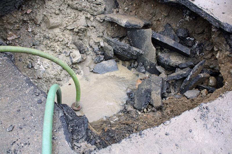 Two pumps are being used to lower the water level inside the hole between diggings of dirt, gravel, rocks and pavement. (Photo by Holly S. Edwards)
