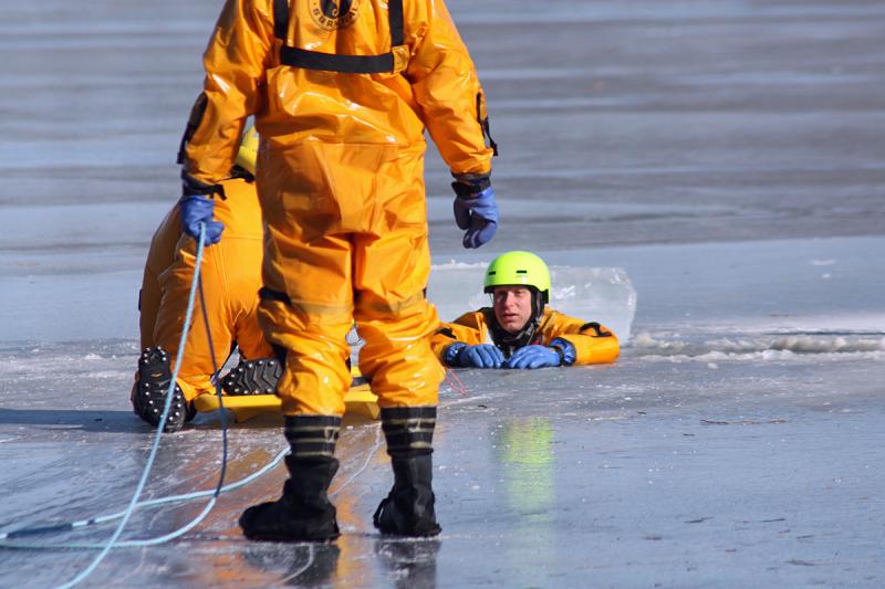 Firefighter Mike Cole is in the water as Brian Sullivan slides closer on the ice rescue sled. (Photo by Holly S. Edwards)
