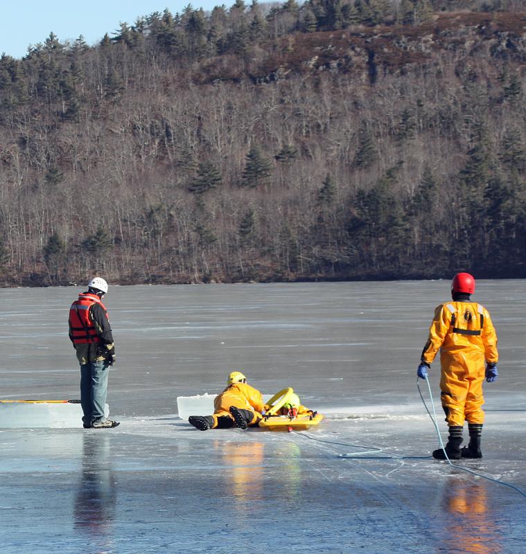 Firefighter Brian Sullivan moves the rescue sling onto Mike Cole, who is playing the victim in the frigid water. (Photo by Holly S. Edwards)