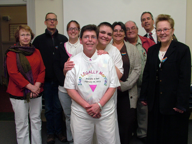 Newlyweds Gabrielle Eiholzer, center left, and Opal Ash, center right, flanked by family, friends and city officials after their wedding ceremony at City Hall. (Photo by Ethan Andrews)