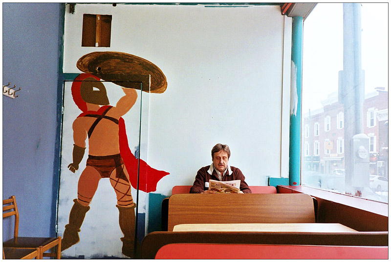 BELFAST - A partially-completed mural of a Spartan warrior at Alexia's Pizza painted by Maleah Chadwick of Searsmont . Owner Ted Rakis, who was born within a mile of the tomb of King Leonidas in Sparta, sits in his customary seat at the restaurant. BELFAST - A partially-completed mural of a Spartan warrior at Alexia's Pizza painted by Maleah Chadwick of Searsmont . Owner Ted Rakis, who was born within a mile of the tomb of King Leonidas in Sparta, sits in his customary seat at the restaurant. (Photo by Ethan Andrews)