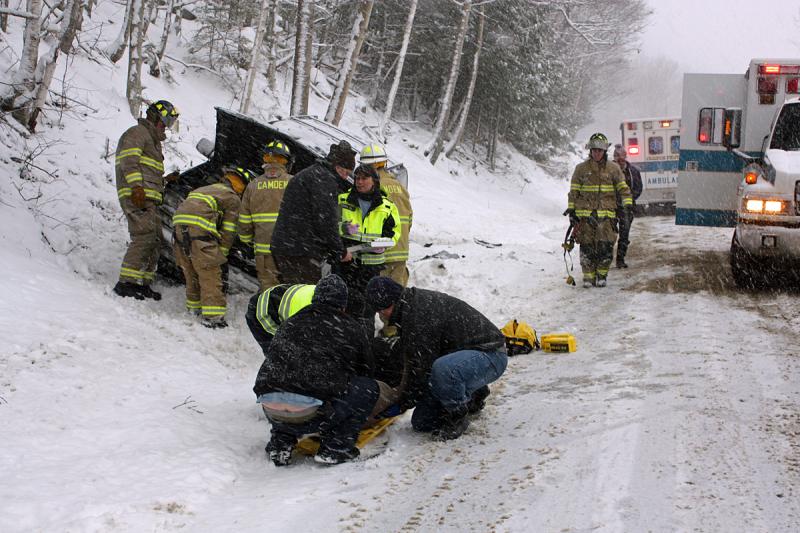 Camden First Aid Association emergency medical technicians prepare to transport Cheryl Battles, of Camden, to the hospital while Camden firefighters check out the Chevrolet sport utility vehicle Battles was a passenger in following a crash on Route 52 early Sunday afternoon. (Photo by Holly S. Edwards)