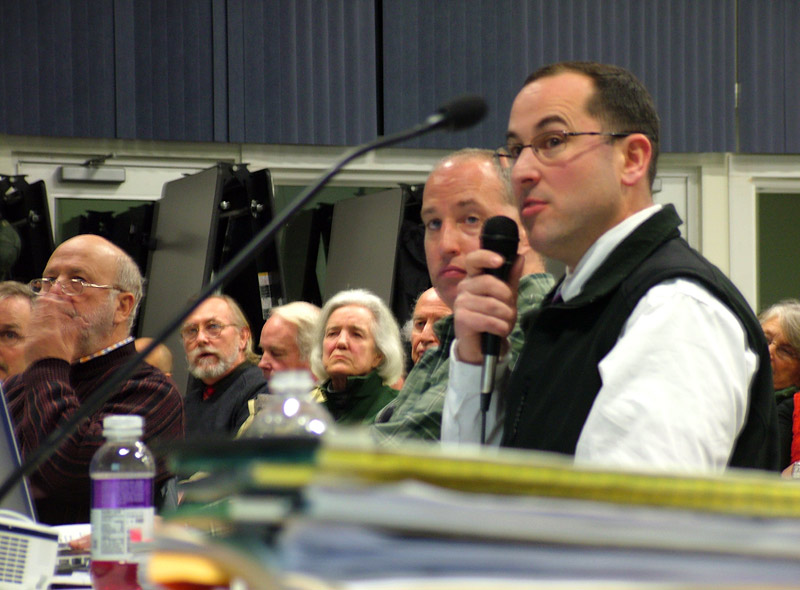 Mike Lucy, with microphone, and Frank Gallagher, behind Lucy, of the security risk consulting firm Good Harbor, detail their company's report to the Searsport Planning Board and roughly 200 people in attendance at a public hearing on Monday night (Photo by Ethan Andrews)
