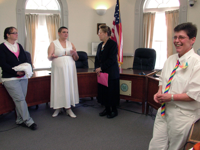Gabrielle Eiholzer, far right, and Opal Ash, second from left, dressed in white with rainbow accents for their wedding at City Hall, Feb. 25, the first marriage of a same-sex couple in Belfast. (Photo by Ethan Andrews)