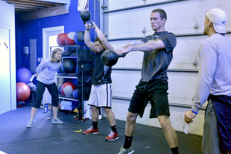 Local athletes Drew Townsend, right, and Daniel Hendricks are spotted and scored by coaches Jason Foster, far right and Teel Foster, owners of the CrossFit Crossover Box in Thomaston during the March 9 Throwdown. (Photo by Ron Hawkes)