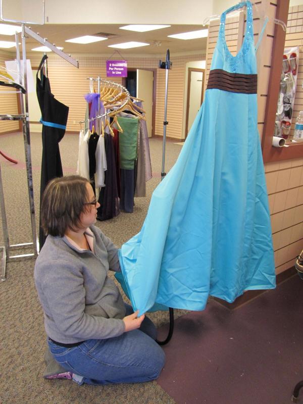 Planning committee member Mandie Sawyer steams a dress for Mariah to try on. (Photo by Kay Stephens) Cinderella Project of Maine
