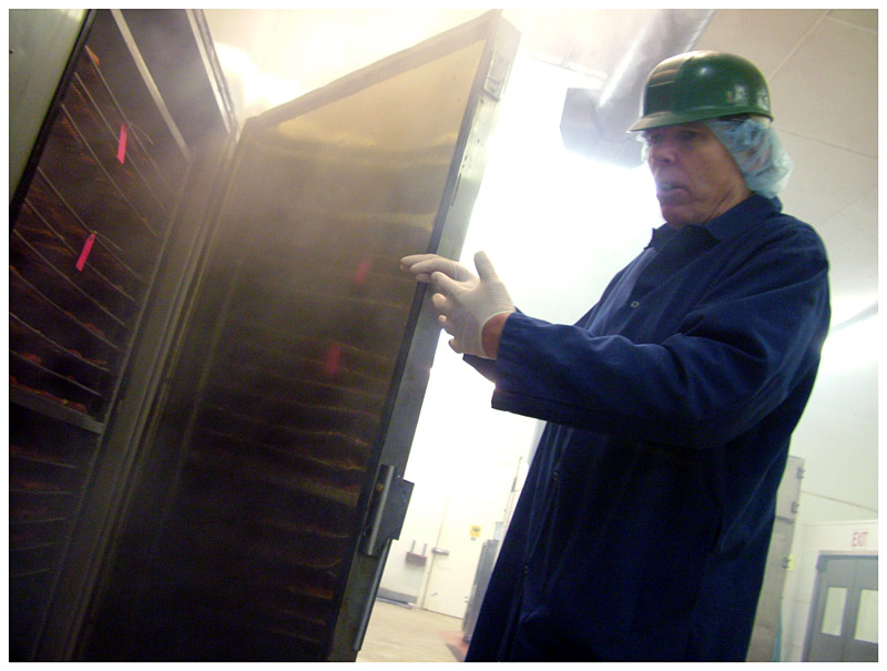 Ducktrap River of Maine's longtime smokehouse operator, Leo Lynch, shows the racks of salmon inside one of the Belfast facility's smokers. (Photo by Ethan Andrews)