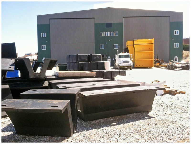 Along the Harbor Walk route, components for a set of fenders for a nuclear submarine — black in the foreground, yellow in the background — await assembly at Front Street Shipyard. (Photo by Ethan Andrews)