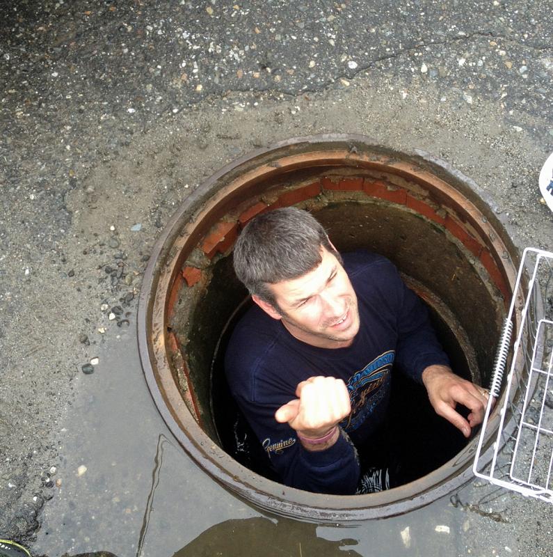 Camden Asst. Fire Chief Andrew Lowe reports his findings, 'Can't reach the ducklings' from inside the storm drain catch basin Friday. (Courtesy Steve Pixley)