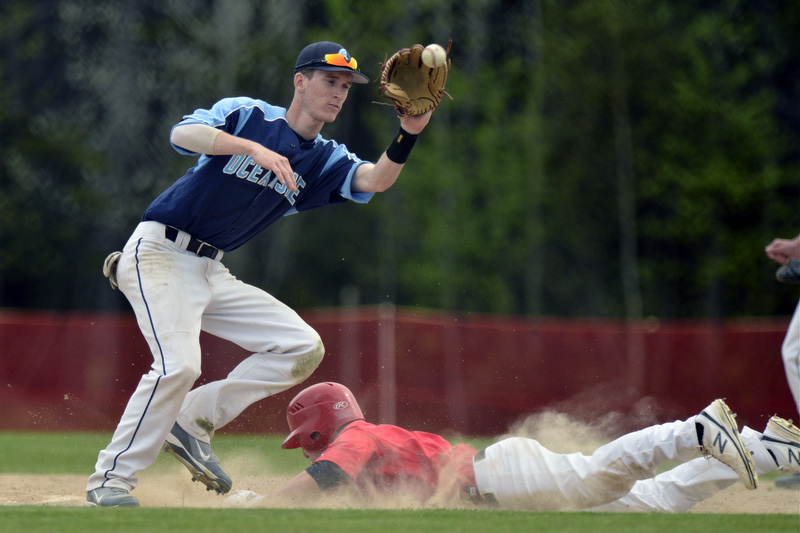 Camden Hills Joe Chamberlain, right, slides in under the tag of Oceanside's shortstop Drew Townsend. (Photo by Ron Hawkes)