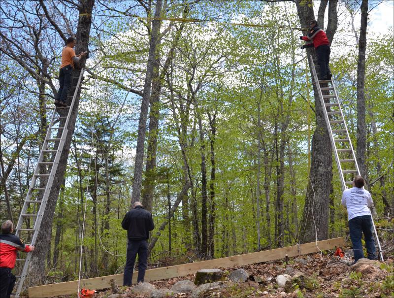 Camden firefighters Eric Verite and Andrew Lowe climb the ladders, while Chief Chris Farley, Cheyne Hansen and Camden First Aid's Brian Allen prepare to hoist the beam into place high in the trees. Competitors in the first-ever Run For Your Life obstacle course race will be climbing ropes to the top of the beam. (Photos by Lynda Clancy)