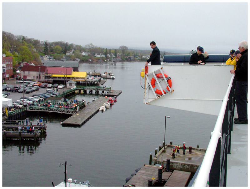 Capt. David Gelinas of the Penobscot Bay & River Pilots Association looks down at the water in Castine Harbor from the upper deck of Maine Maritime Academy's Training Ship State of Maine for clues about the direction of the tide. (Photo by Ethan Andrews)