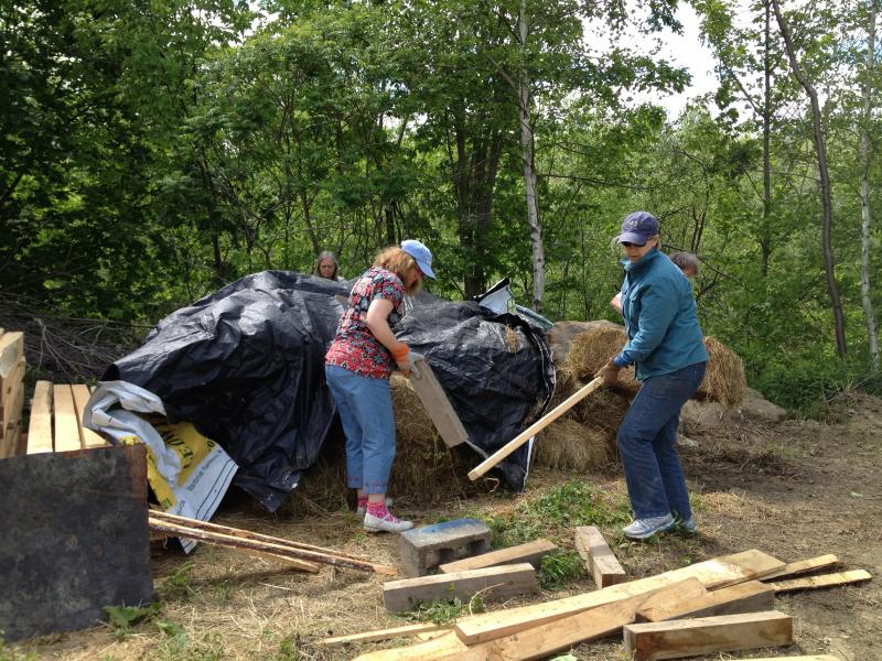 Barbara Biscone, left, and Jill Harvey sort wood for the sheds that will house antique farm implements next to the Lincolnville Community Library. (Photo by Sheila Polson)