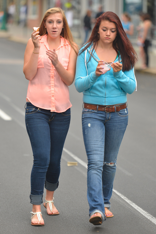 Rachel Philbrook, left, and Brittaney Mahonen enjoy some ice cream while strolling Main St. during the Summer Solstice. (Photo by Ron Hawkes)